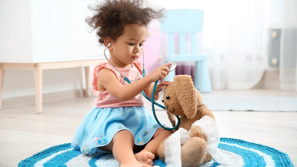 una niña juega al doctor con un peluche