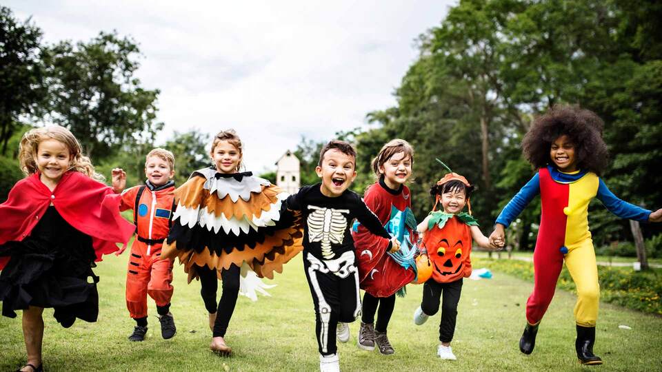 niños disfrazados corriendo alegres en el parque