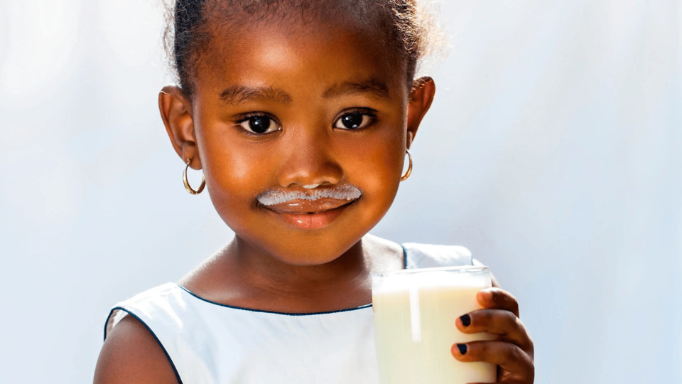 Niña tomando un vaso de leche, ideal para su crecimiento y desarrollo