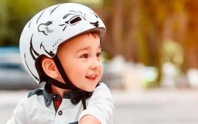 niño con casco montando monopatin