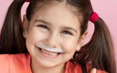 niña alegre tomando  un vaso de leche