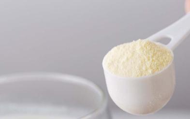 Una persona preparando un vaso de leche deslactosada en polvo  