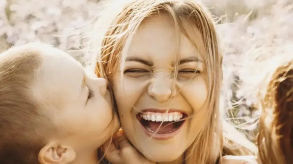 Mamá sonrie mientras su hijo le da un beso