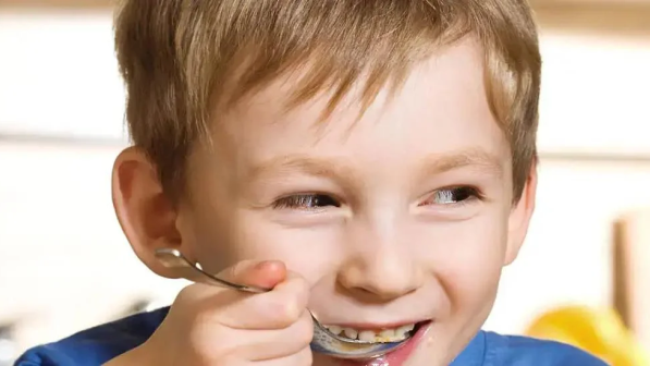 niño con la cuchara en la boca
