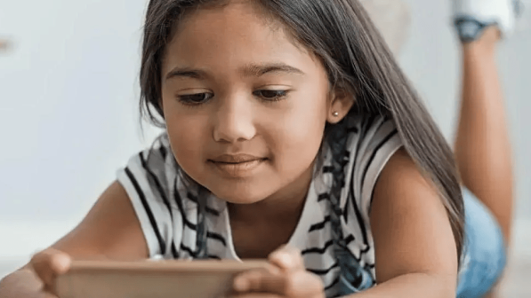 niña mira un celular acostada