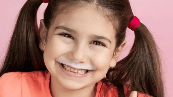 niña alegre tomando un vaso de leche