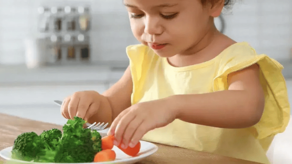 Niña comiendo verduras